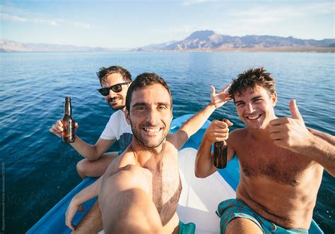 Group Of Three Men Friends Taking A Selfie On A Boat With Beautiful