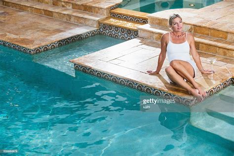 Mature Woman Sitting At The Edge Of A Swimming Pool High Res Stock