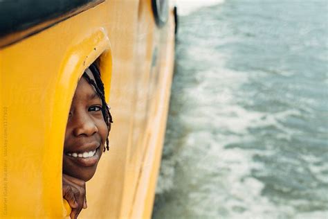 view smiling black girl peeking out of a boat window by stocksy contributor gabriel gabi