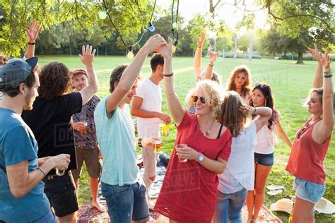 Crowd Of Adult Friends Dancing At Party In Park At Sunset Stock Photo