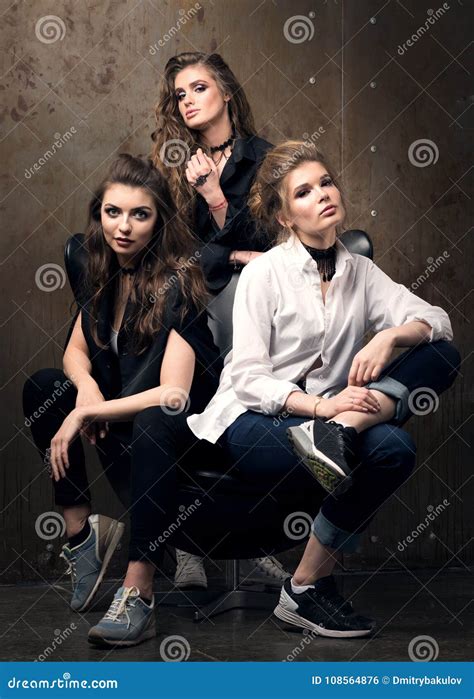 Vertical Portrait Of Three Beautiful Young Women Posing On A Chair