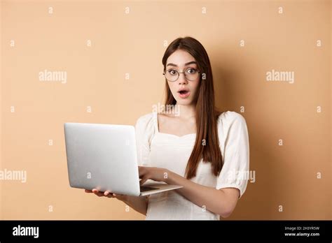 Surprised Girl Using Laptop And Gasping Amazed Say Wow Looking In Glasses At Camera Beige