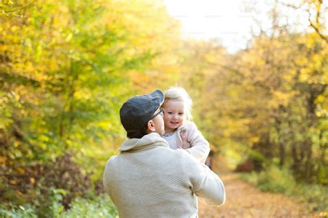 father holding his little daughter spinning her walk in colorful autumn forest photo