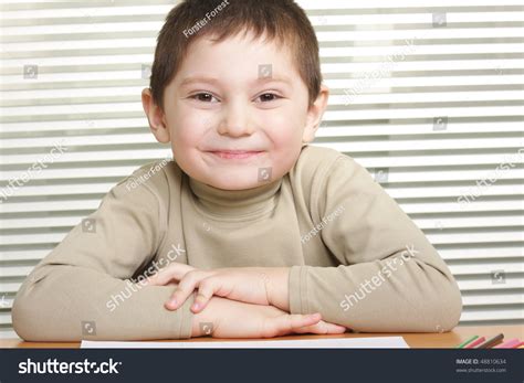 Little Smiling Boy Sitting At Desk Hands Folded Stock Photo 48810634