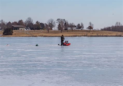 Ice Fishing Frozen Lake Surface In Winter With Ice Fisherman On The