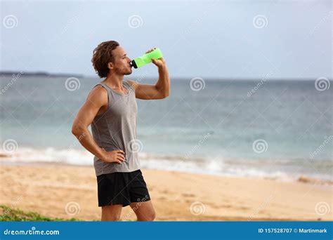 Fitness Runner Man Drinking Water Bottle During Summer Heat At Beach