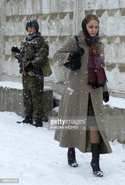 A Chechen Woman Walks Past A Russian Soldier During A Heavy Snowfall