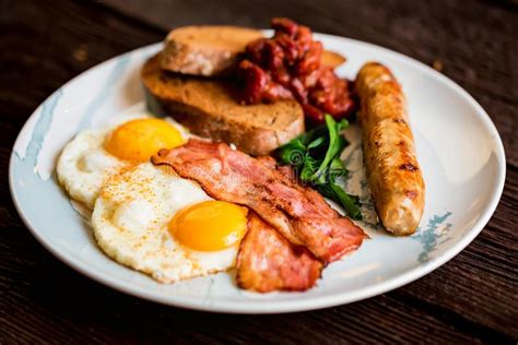 Typial Breakfast With Eggs Bacon And Sausage On Plate Stock Photo