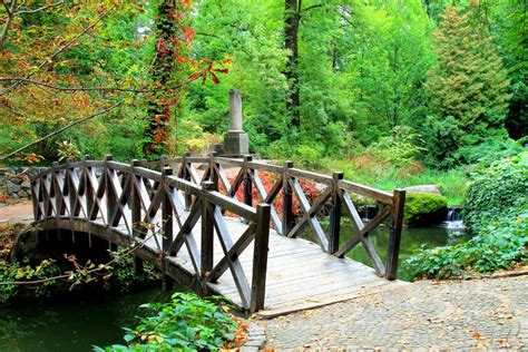Old Red Wooden Bridge Across Small River In A Green Park Vintage