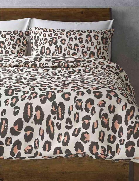 A Bed With A Leopard Print Comforter And Pillows