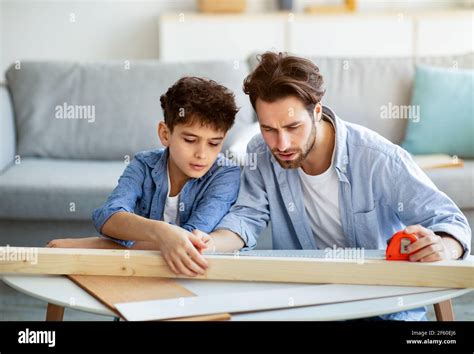 concentrado padre e hijo medir tabla de madera con cinta hombre enseñando niño haciendo tareas