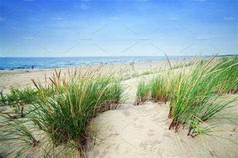 Beach With Dunes And Green Grass Featuring Beach Sand And Ocean