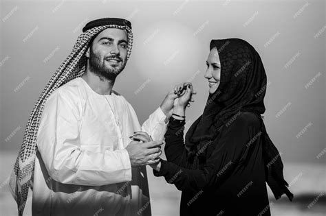 Couple Habillé à La Manière Arabe Posant Sur La Plage Au Lever Du Soleil En Noir Et Blanc