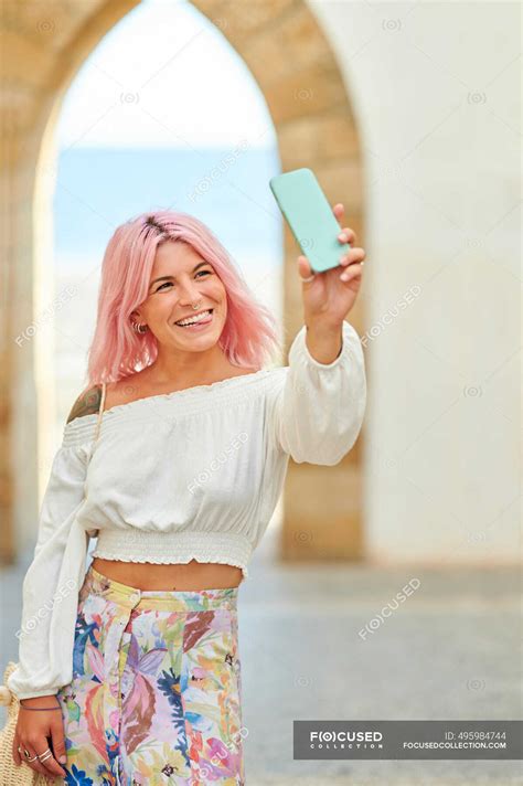 Young Woman Sticking Out Tongue While Taking Selfie Through Mobile