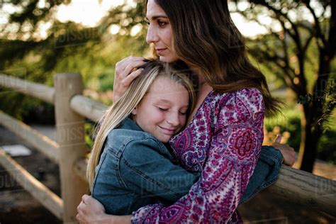 Mom Hugging Daughter while daughter smiles in SoCal - Stock Photo 