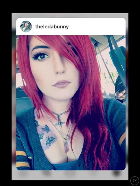 a woman with red hair and piercings on her chest is taking a selfie