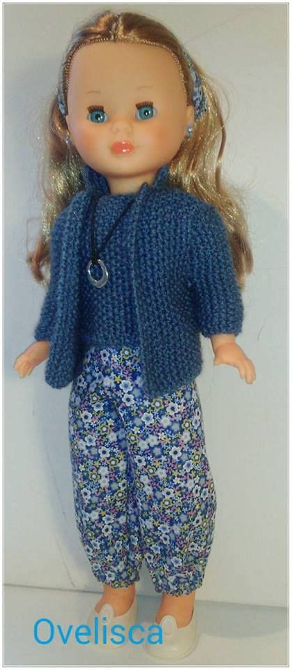 A Doll With Blonde Hair Wearing Blue Pants And A Knitted Cardigan