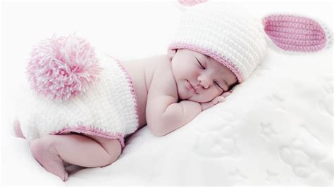 Cute Baby Is Sleeping On White Bed Wearing White Bunny Woolen Netted