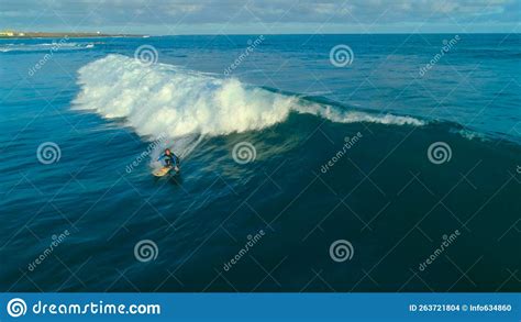 Aerial Young Male Surfer Carving A Tube Wave Glistening In Bright