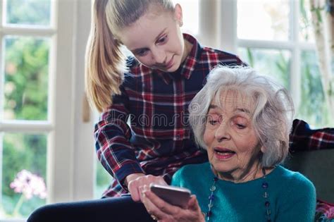 Teenage Granddaughter Showing Grandmother How To Use Mobile Phone Stock