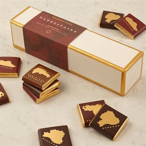 Some Chocolates Are Sitting On A Table Next To A Box With Gold Trimming