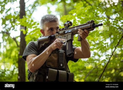 A Man Standing With An Airsoft Assault Rifle In Military Uniform In The