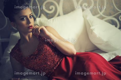 Attractive Brunette Woman In Elegant Red Dress Lying On Sofa