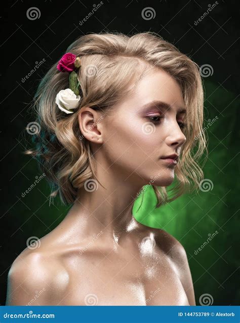 Het Mooie Jonge Blondemeisje Met Naakte Die Schouders Bloemen In Haar