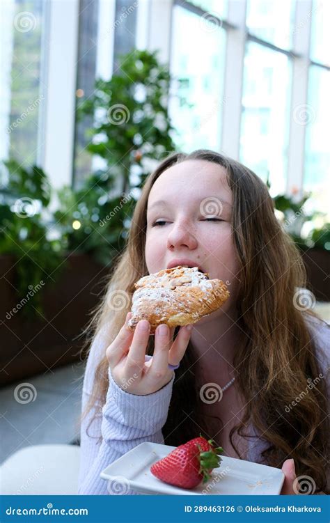 Close Up Of Hungry Starving Red Haired Girl Eating Croissant Staring At