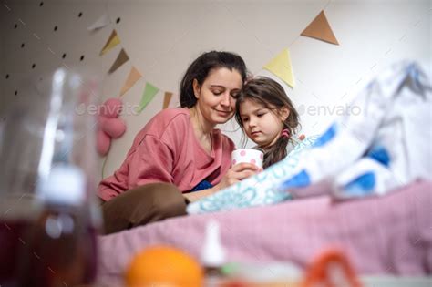 Mother Looking After Sick Small Daughter In Bed At Home Stock Photo By