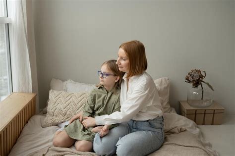 Madre e hija sentadas en la cama en casa mamá e hija se abrazan y se miran Foto Premium
