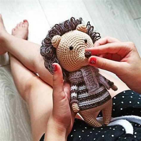 A Woman Is Holding A Crocheted Hedge Doll In Her Hands While Sitting On