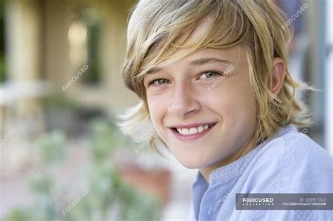 Portrait Of Smiling Teenage Boy With Blonde Hair Outdoors — Looking At