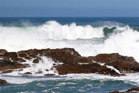 A Big Wave Crashing Into The Rocks In The Rough Wild Water Of The Ocean