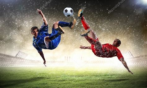 Two Football Players In Jump To Strike The Ball At The Stadium — Stock