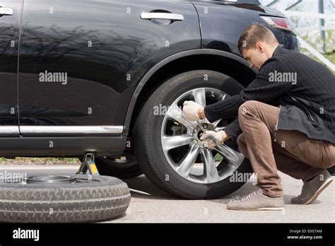 Man Changing His Spare Wheel Replacing The Original Tyre With A Fixed Puncture Tightening The