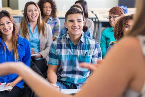 Teens Smiling While Listening To Speaker During Presentation In School