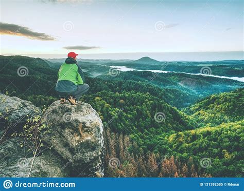 Man Stands On The Peak Of Rock Hiker Watching To Autumn Sun At Horizon