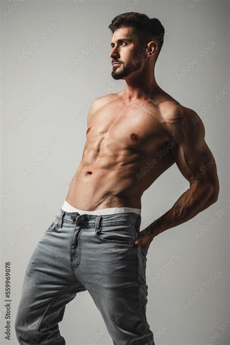 Male Model With Perfect Body In Jeans Posing Over Grey Background Close Up Studio Shot Stock