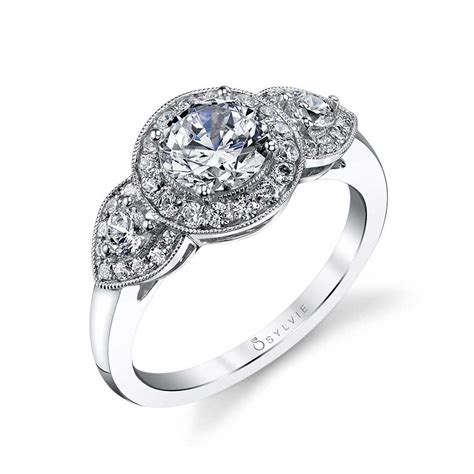 Featuring two round brilliant diamonds precisely cut to frame a third round brilliant center stone, this tiffany three stone diamond engagement ring features a shared setting to provide the highest possible level of radiance. Sandrine - Three Stone Halo Engagement Ring - SY447
