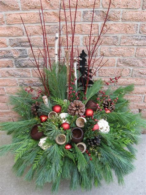 A Christmas Centerpiece With Pine Cones Berries And Greenery In Front