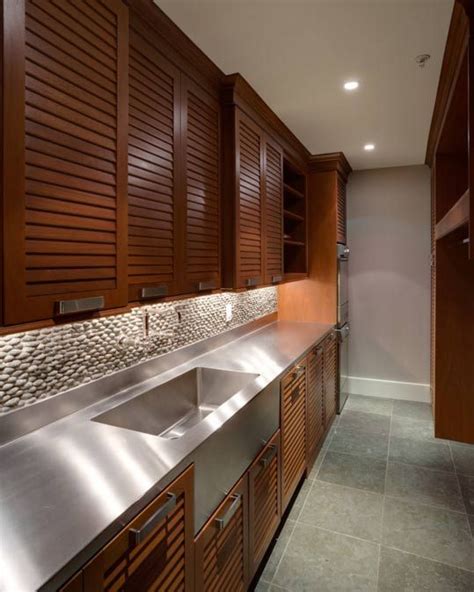 A Kitchen With Stainless Steel Sinks And Wooden Cabinets