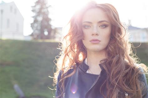 Beautiful Red Haired Girl In The Sun In A Black Jacket In The Town Park