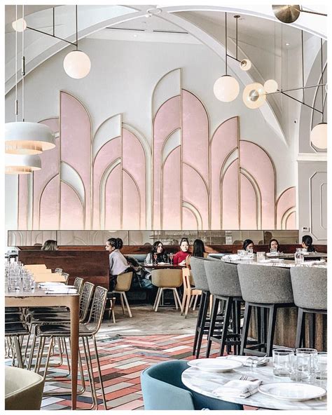 People Sitting At Tables In A Restaurant With Pink Walls And Arched