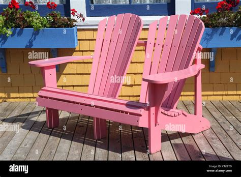 Double Pink Wooden Adirondack Chairs Sit On A Wooden Deck Stock Photo