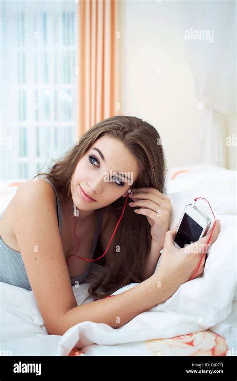 Portrait Of Teenage Girl Lying On Bed And Hearing Music With Headphones