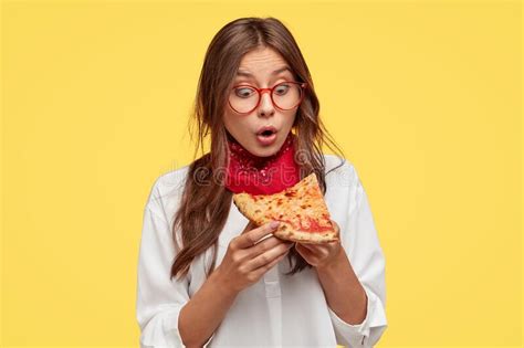shocked emotive lady looks with surprisement at slice of pizza amazed with its wonderful taste