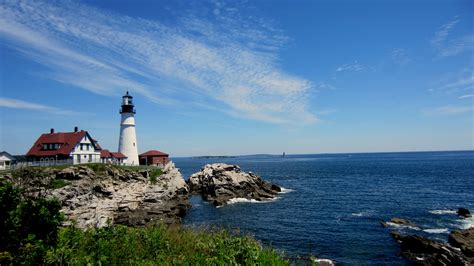 A Light House Sitting On Top Of A Rocky Cliff Next To The Ocean Under A