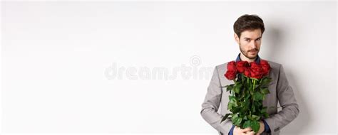 Handsome Macho Man Going On Date In Suit Holding Bouquet Of Red Roses And Smiling At Camera