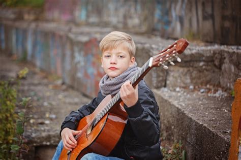 Niño Pequeño Que Toca La Guitarra En Día Frío Del Otoño Foto Premium